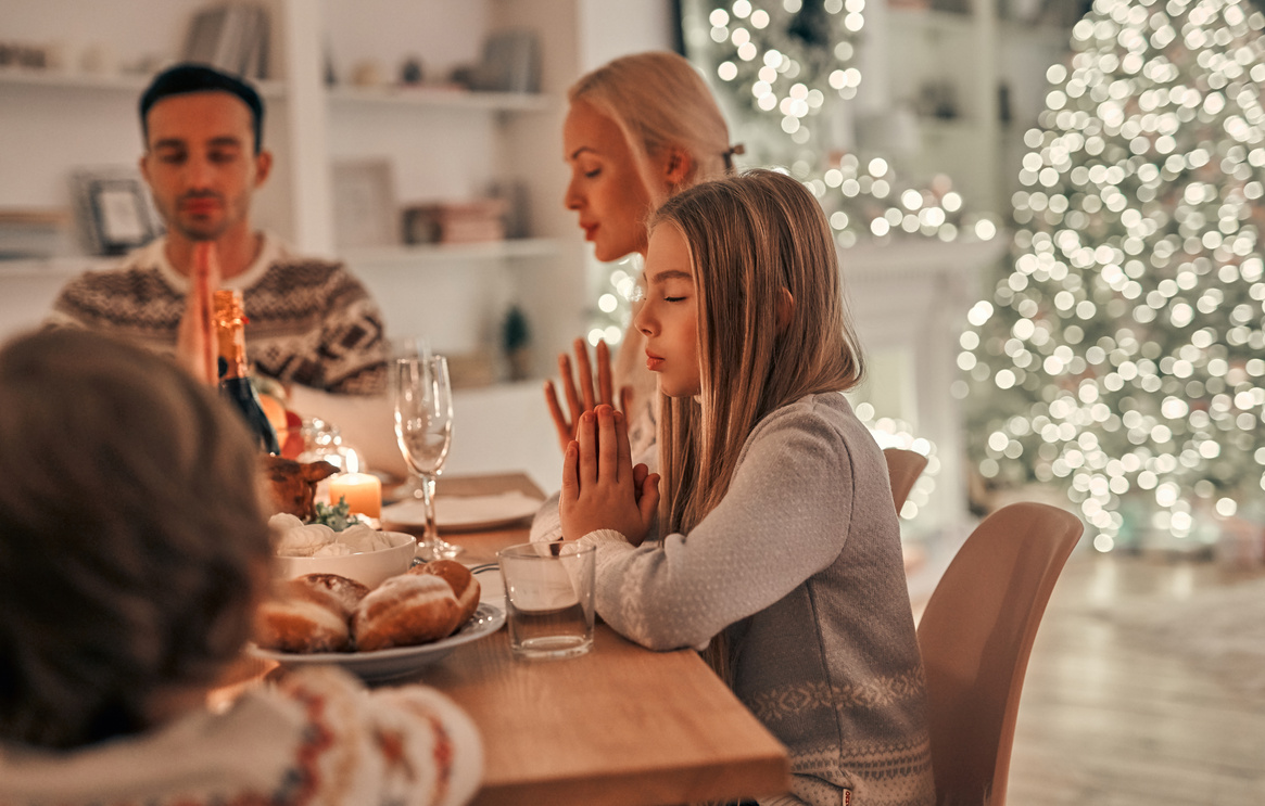 The happy family praying at the christmas table